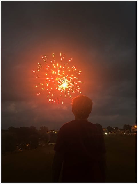 My son watching a firework explode in the distance.